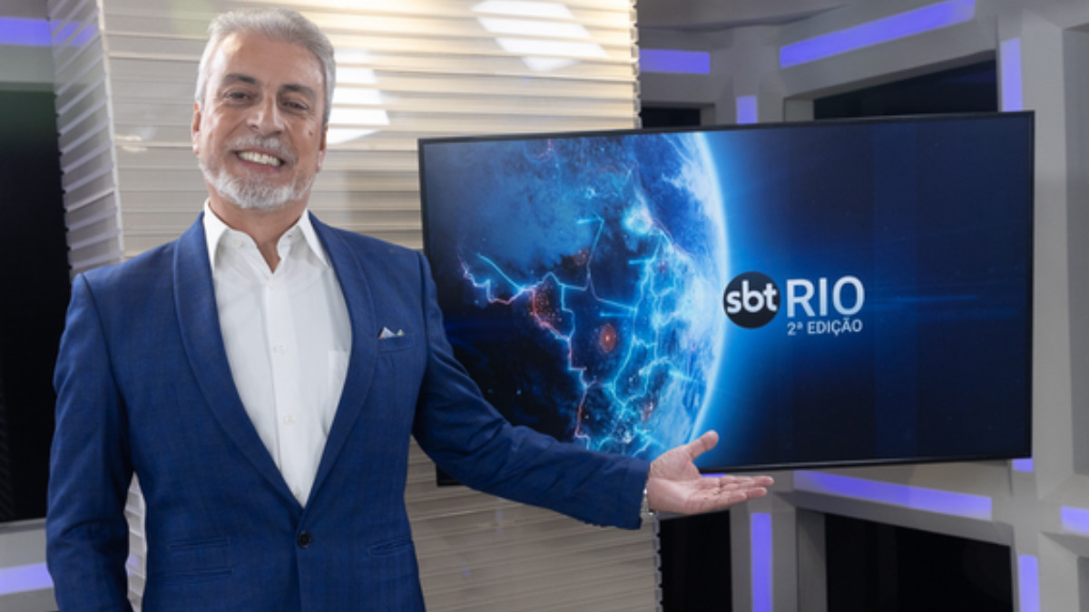 Clóvis Monteiro nos estúdios do SBT Rio 2 Edição, apontando para um televisor
