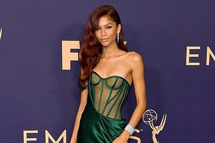 Zendaya de vestido longo verde, pulseira de brilhantes durante passagem no Emmy