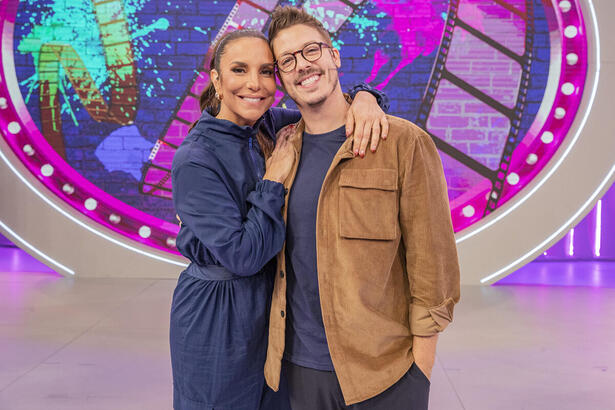 Ivete Sangalo de macaquito jeans azul, sorrindo, com a mão no ombro de Fábio porchat; Fábio porchat de jaqueta marrom, camisa azul, óculos de grau preto, sorrindo, durante gravação do Pipoca da Ivete, da TV Globo