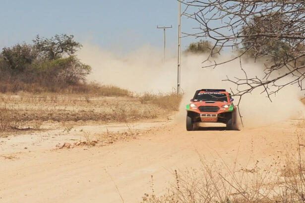 Carro do Rally dos Sertões, em tercho de uma estrada de terra levantando poeira. Trecho do Globo Repórter