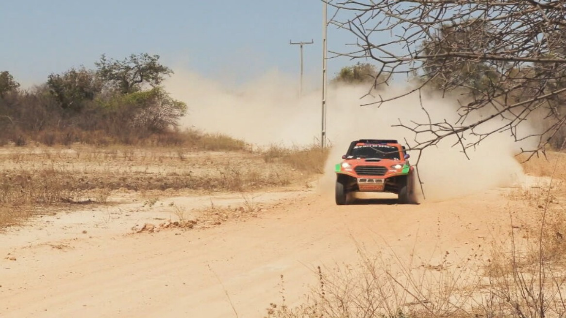 Carro do Rally dos Sertões, em tercho de uma estrada de terra levantando poeira. Trecho do Globo Repórter