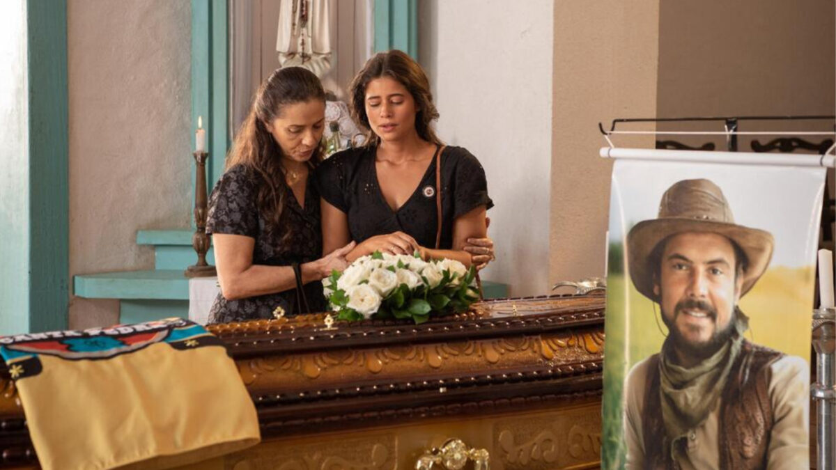 Isadora Cruz e Cyria Coentro em frente a um caixão
