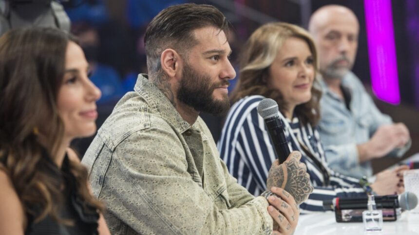 Tania Khalill, de camisa preta, Lucas Lucco de jaqueta jeans bege segurando um microfone com a mão esquerda, Cristina Padiglione com as mãos juntas na bancada de jurados e camisa listrada azul e branco; e Claudio Vargas de camisa social azul clara