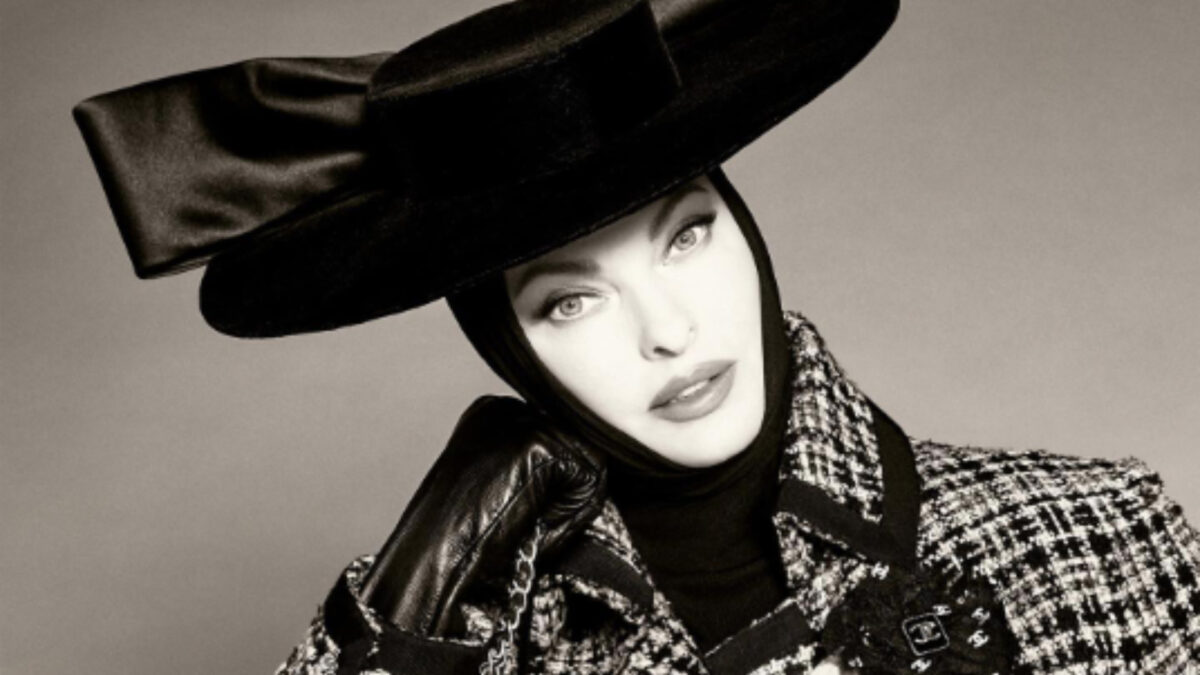 Linda Evangelista toda coberta e com chapéu preto
