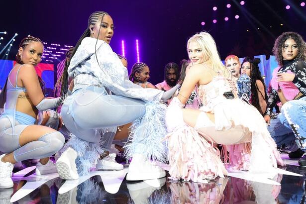 Ludmilla de azul, cabelo em trança, abaixada; Luísa Sonza de rosa abaixada ao lado de Ludmilla e dançarinos durante performance do MTV Miaw 2022