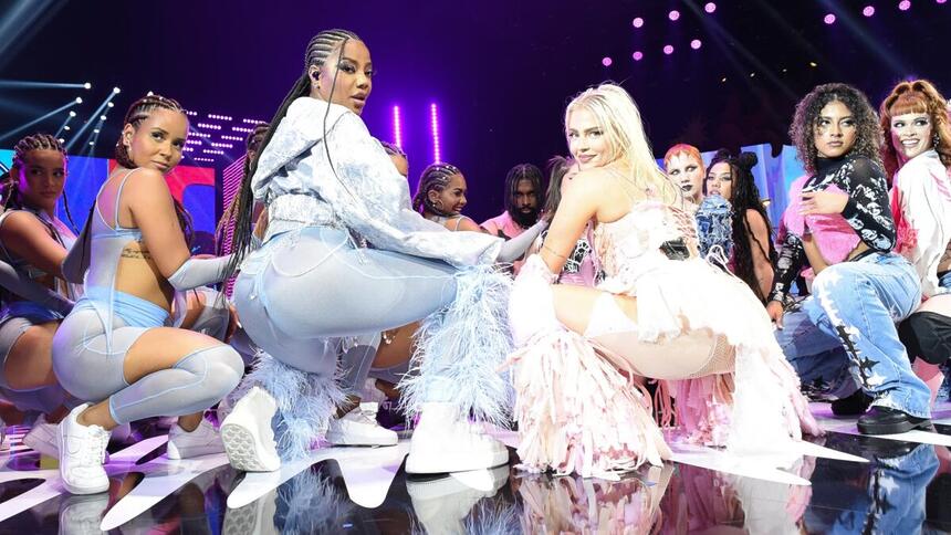 Ludmilla de azul, cabelo em trança, abaixada; Luísa Sonza de rosa abaixada ao lado de Ludmilla e dançarinos durante performance do MTV Miaw 2022