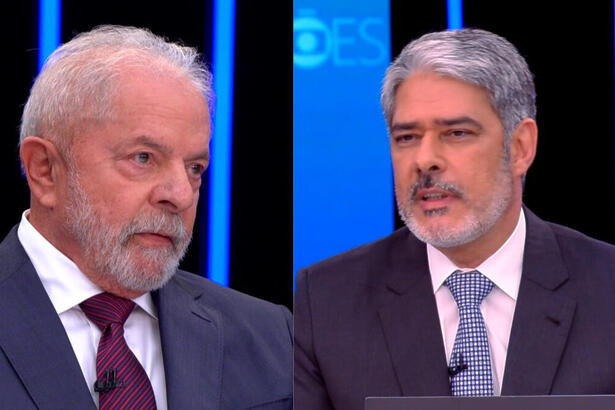 Lula de palitó azul e gravata na cor magenta; William bonner de palitó preto, gravata azul e detalhes brancos com semblante sério