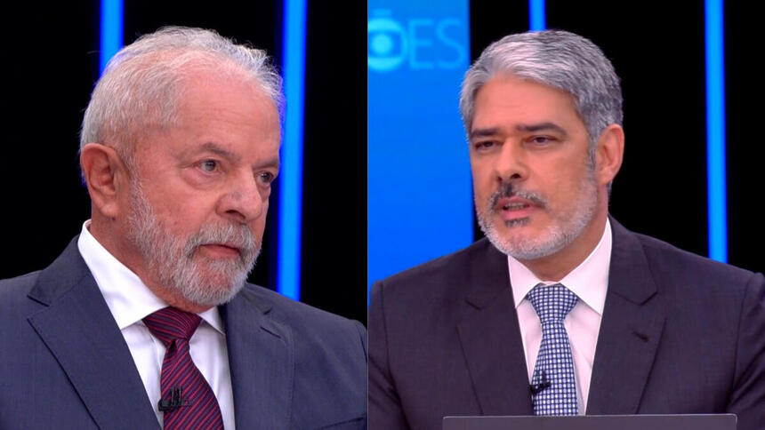 Lula de palitó azul e gravata na cor magenta; William bonner de palitó preto, gravata azul e detalhes brancos com semblante sério