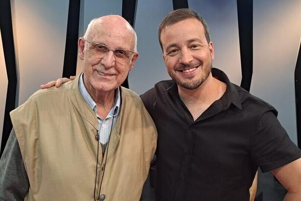 Padre Julio Lancellotti de camisa marrom, com flash no meio, de óculos, sorrindo, ao lado de Rafael Cortez de camisa manga longa preta, sorrindo, durante gravação do Matéria Prima, da TV Cultura