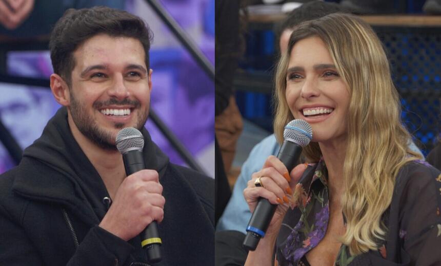 Rodrigo Mussi de camisa preta, segurando o microfone co a mão direita, sorrindo, sentado, durante entrevista no Altas Horas; Fernanda Lima com camisa estampada em tons de lilás e magenta, sorrindo, segurando o microfone com a mão esquerda