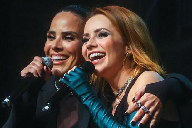 Wanessa Camargo e Sandy sorrindo, cantando, com o microfone próximo a boca durante apresentação da turnê Nós Voz Eles 2 em São Paulo