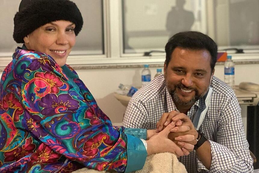 Simony e Geraldo Luís de mãos dados em uma foto no hospital. Simony está com uma touca da cabeça, sem aparecer os seus cabelos já ralos por causa do tratamento