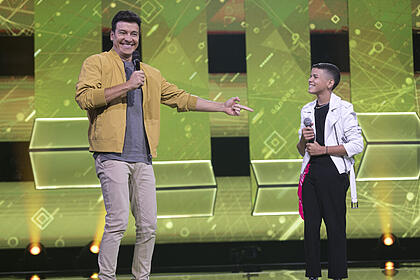 Rodrigo Faro estende o braço para Vinicius o Vaqueirinho no palco do Canta Comigo Teen 3
