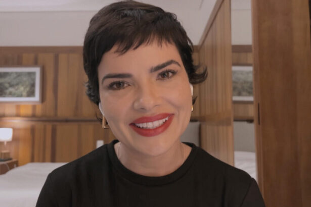 Vanessa Giácomo de cabelo curto para novo personagem, sorrindo, de batom vermelho e camisa preta durante entrevista para Pedro Bial