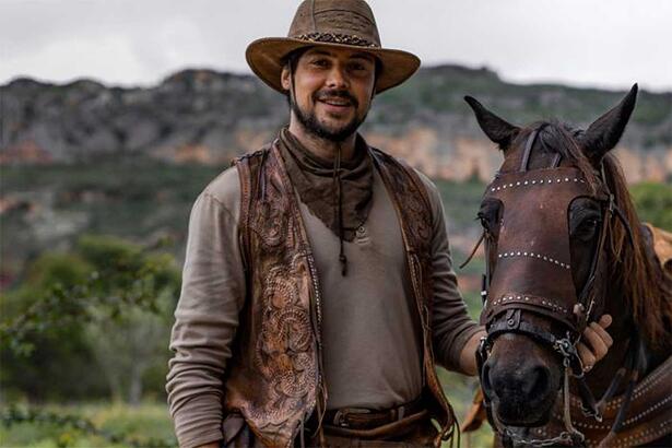 Sérgio Guizé de chapéu e com cavalo ao lado