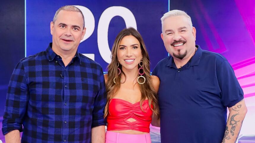 Bola de camisa lisa na cor azul marinho ao lado de Patricia Abravanel de camisa vermelha e calça rosa ao lado de Carioca com camisa estampada nas cores azul e preta durante gravação do programa Silvio Santos, do SBT