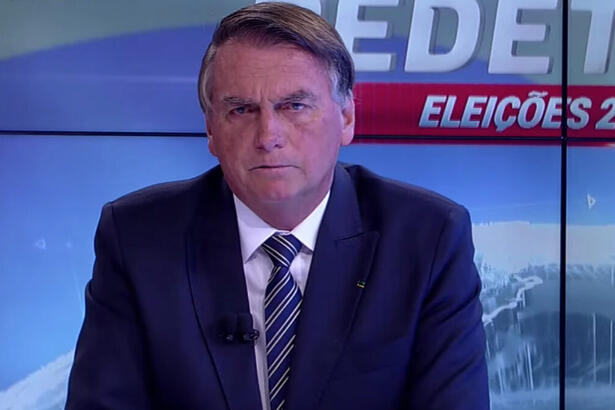 Bolsonaro de palitó, preto, gravata listrada preta a branca, camisa social branca, sentado durante entrevista na RedeTV!