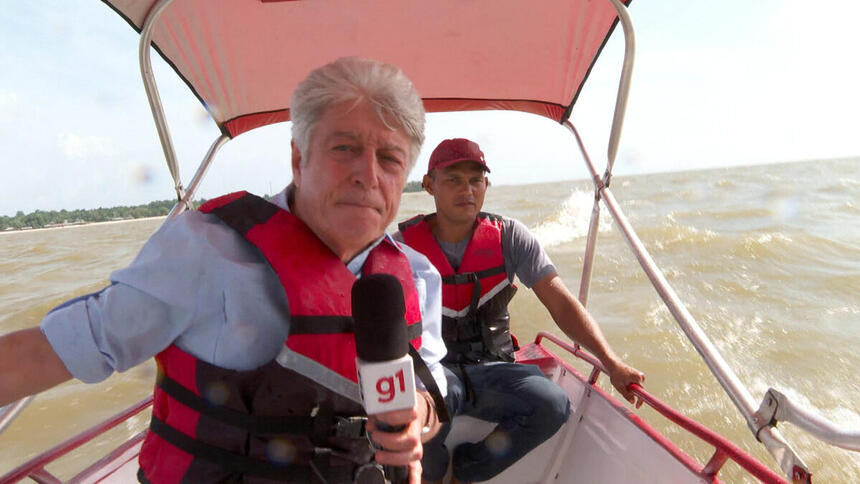 Caco Barcellos ao lado de outro rapaz, em uma lancha dentro de um rio no Pará