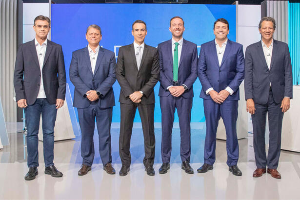 Rodrigo Garcia (PSDB), Tarcísio de Freitas (Republicanos), Vinicius Poit (NOVO), Elvis Cezar (PDT) e Fernando Haddad (PT) posicionados no estúdio do debate na TV Globo, ao lado de Cesar Tralli