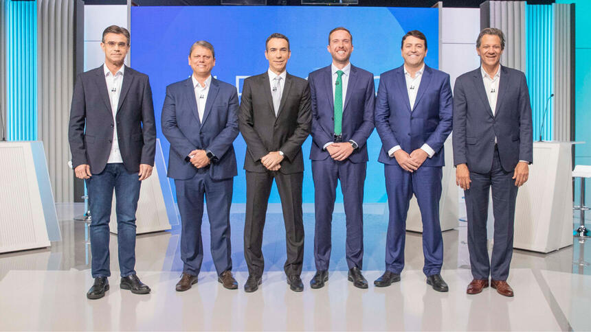 Rodrigo Garcia (PSDB), Tarcísio de Freitas (Republicanos), Vinicius Poit (NOVO), Elvis Cezar (PDT) e Fernando Haddad (PT) posicionados no estúdio do debate na TV Globo, ao lado de Cesar Tralli