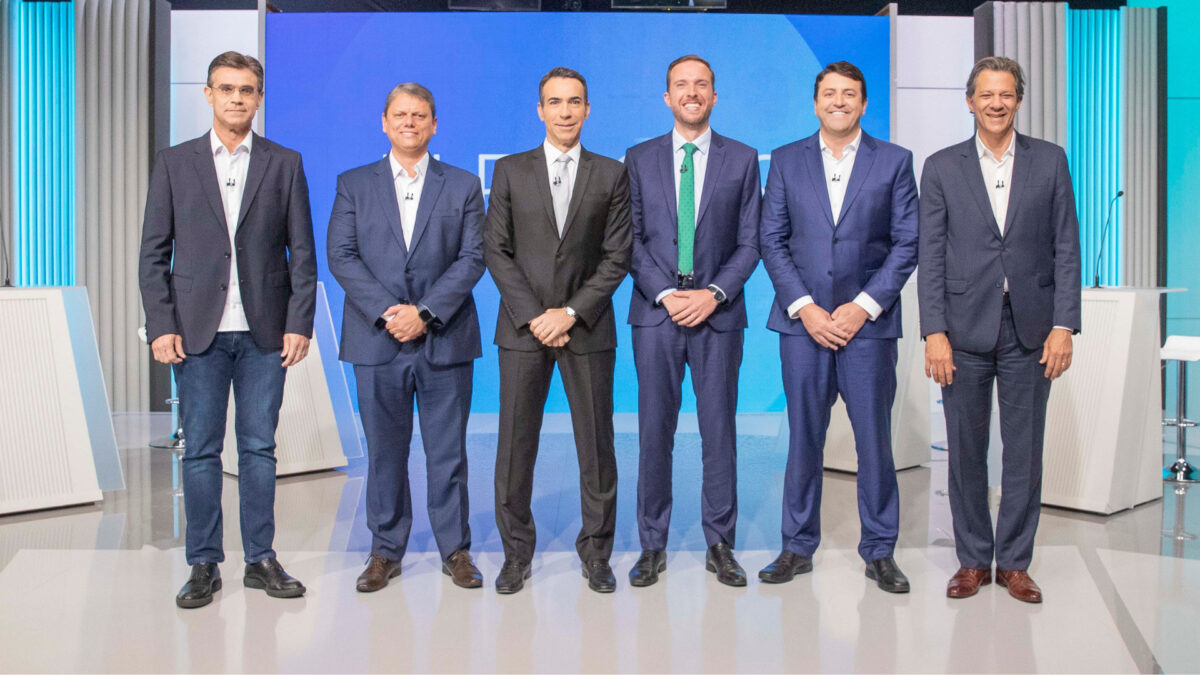Rodrigo Garcia (PSDB), Tarcísio de Freitas (Republicanos), Vinicius Poit (NOVO), Elvis Cezar (PDT) e Fernando Haddad (PT) posicionados no estúdio do debate na TV Globo, ao lado de Cesar Tralli