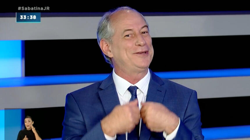 Ciro Gomes com a mão na gravata, sorrindo, durante entrevista na Record TV