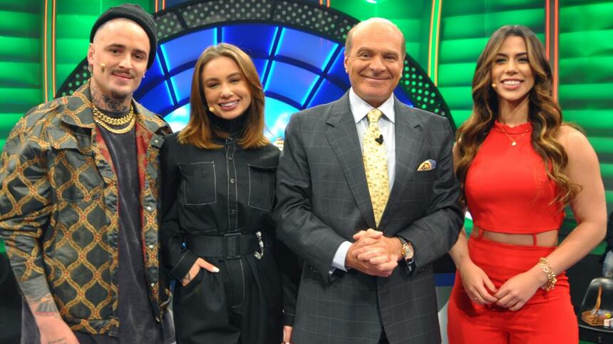 Caique Gama de camisa e boina pretos, sorrindo; Flávia Gabê de vestido preto, com as mãos nos bolsos, Larissa Tamásea de top e calça vermelha, sorrindo ao lado de Marcelo de Carvalho durante gravação do O Céu é o Limite, da RedeTV!