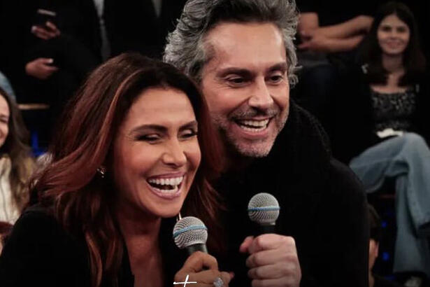 Giovanna Antonelli abraçada com Alexandre Nero, sorrindo e segurando microfone durante gravação do Altas Horas, da TV Globo