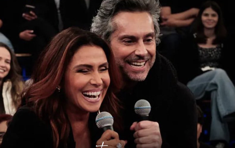 Giovanna Antonelli abraçada com Alexandre Nero, sorrindo e segurando microfone durante gravação do Altas Horas, da TV Globo