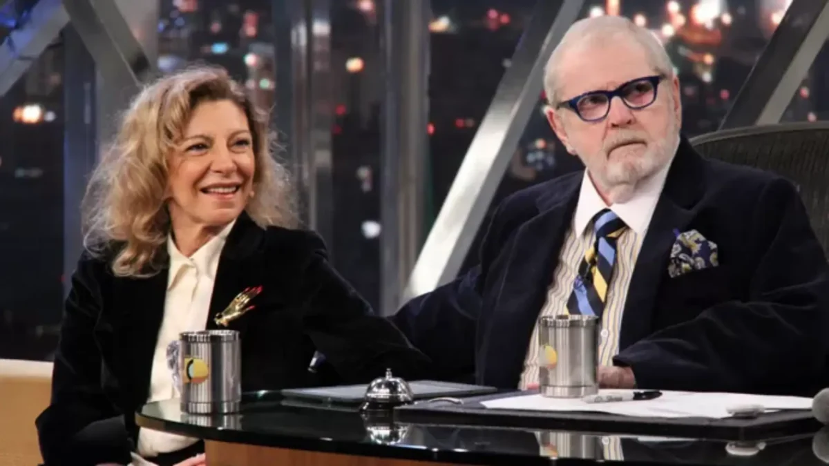 Marília Pêra de blazer preto, camisa social branca sorrindo, sentada ao lado de jô soares durante gravação