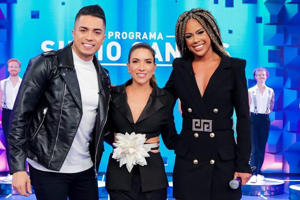 Raffa Augusto de jaqueta de couro, camisa branca, calça jeans preta sorrindo ao lado de Patricia Abravanel e Marvvila de vestido preto