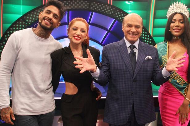 Matheus de camisa manga longa cinza e calça preta, sorrindo; Brenda Paixão de vestido decotado preto, sorrindo; Marcelo de Carvalho sorrindo, com as mãos e dedos abertos; Cintia de vestido rosa durante gravação de O Céu é o limite, da RedeTV!