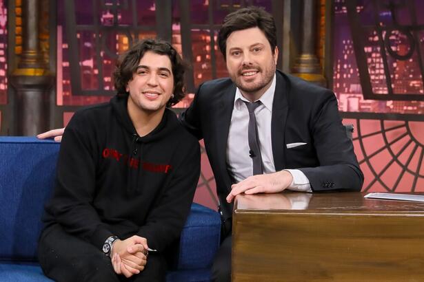 Nattan de camisa e calça preta, sentado ao lado de Danilo Gentili durante gravação do The Noite, do SBT