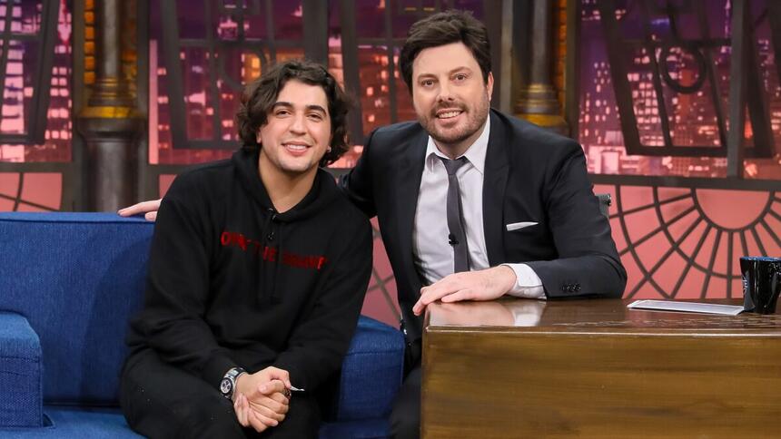 Nattan de camisa e calça preta, sentado ao lado de Danilo Gentili durante gravação do The Noite, do SBT