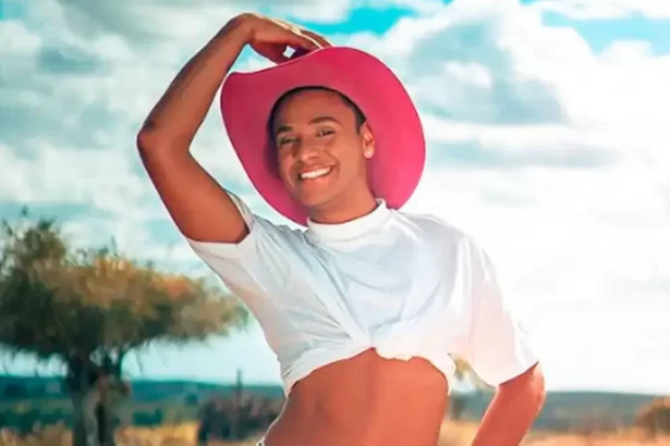 Ney Lima sorrindo, segurando um chapéu de cowboy rosa com a mão direita durante ensaio fotográfico para as redes sociais