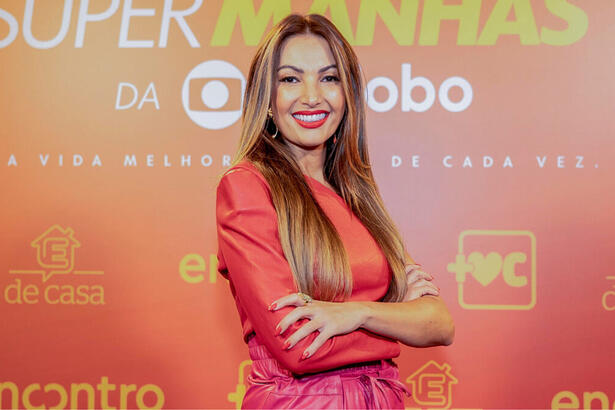 Patrícia Poeta em frente ao banner de divulgação das super manhãs da TV Globo