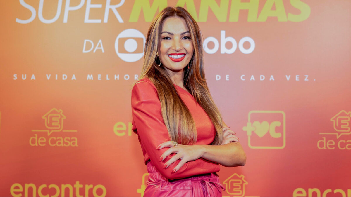 Patrícia Poeta em frente ao banner de divulgação das super manhãs da TV Globo