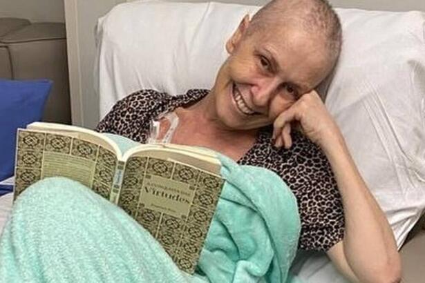 Susana Naspolini deitada em um leito de hospital, lendo um livro