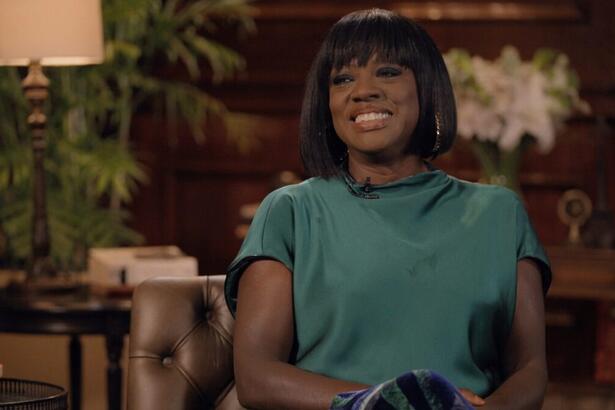 Viola Davis de camisa verde, sorrindo, de cabelo curto, liso, de franja, durante entrevista com Pedro Bial