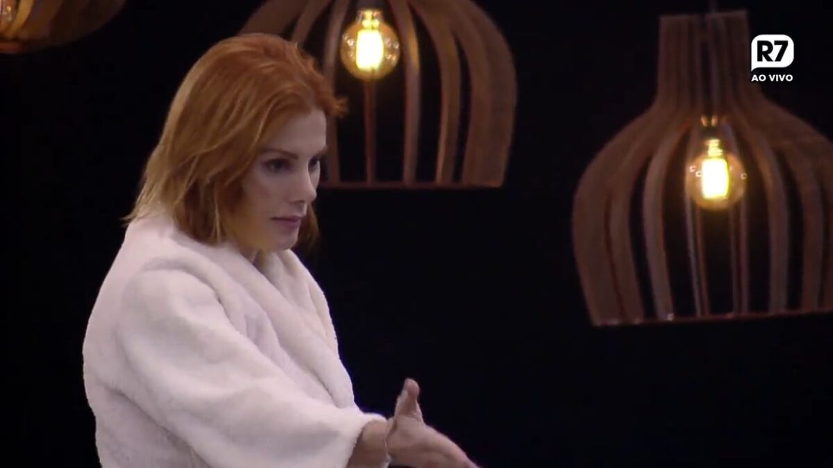Deborah com um roupão com semblante sério.