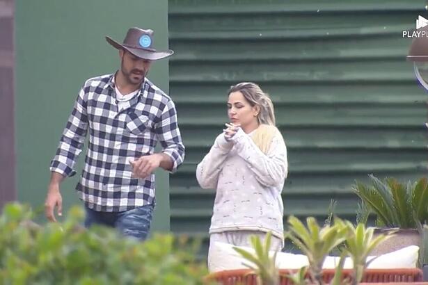 Shay de camisa xadrez ao lado de Deolane na área externa de A Fazenda.
