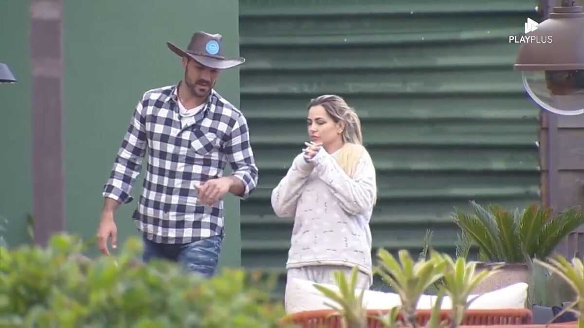 Shay de camisa xadrez ao lado de Deolane na área externa de A Fazenda.