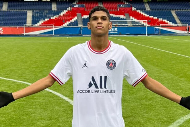 Luva de Pedreiro com os braços abertos com a camisa do PSG, no gramado do estádio Parque dos Príncipes