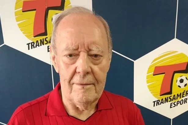 Roberto Carmona em frente a um banner com logo da rádio Transamérica