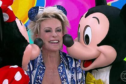 Ana Maria Braga, sendo beijada por Minnie e Mickey, nos estúdios do Mais Você