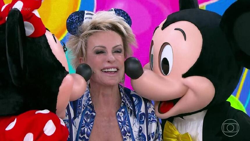 Ana Maria Braga, sendo beijada por Minnie e Mickey, nos estúdios do Mais Você