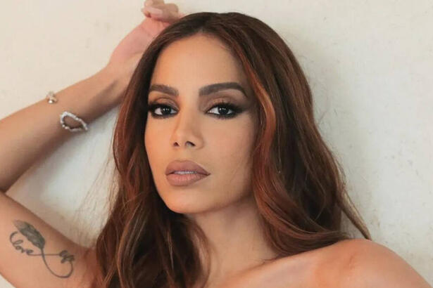 Anitta em foto posada, com a mão direita próximo a cabeça