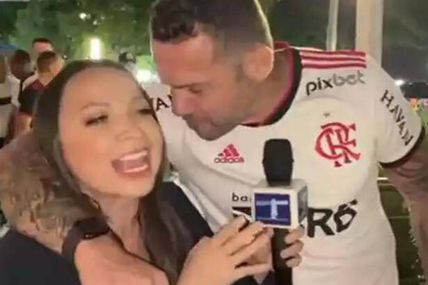 Jornalista abraçada com um torcedor do Flamengo, que tenta beija-la