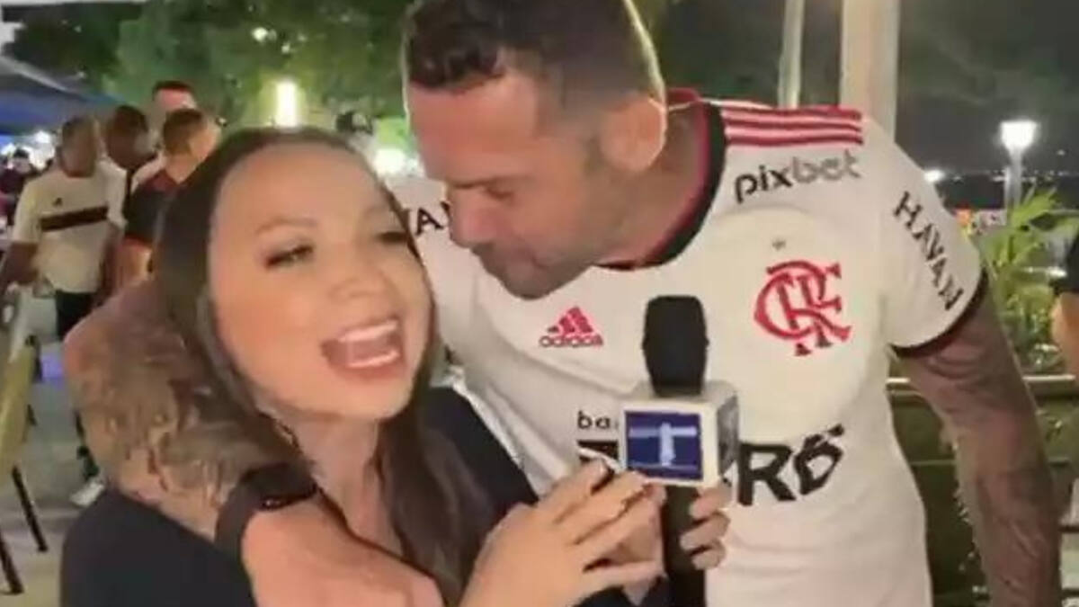 Jornalista abraçada com um torcedor do Flamengo, que tenta beija-la