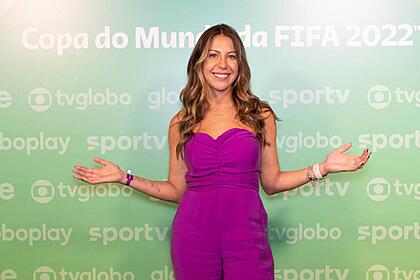 Bárbara Coelho em frente ao banner de divulgação da Copa do Mundo 2022 na Globo